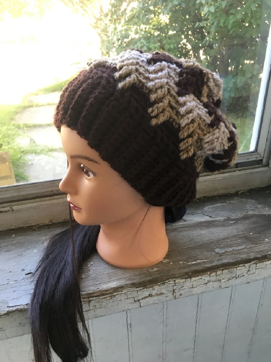 Brunette mannequin wearing a slouchy brown crochet beanie with a light brown and cream zig zag pattern on top.