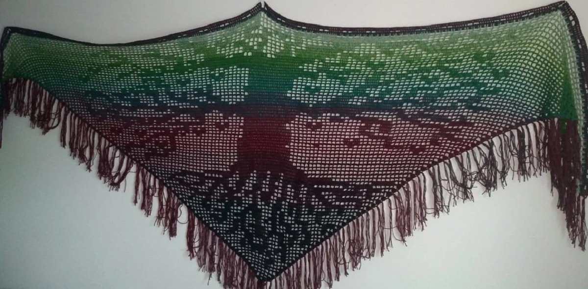 Green, purple, and black crochet shawl with a large tree, its roots, and branches crochet across the center and purple tassels along the bottom.