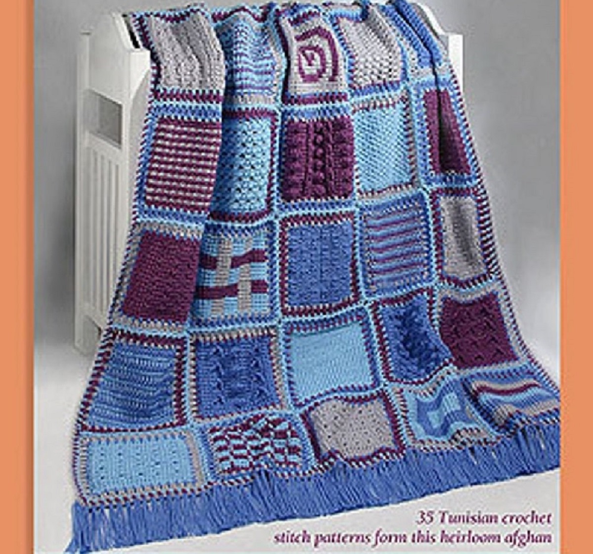 Blue and purple patchwork style crochet Afghan with long blue tassels along the bottom draped over a white crib.