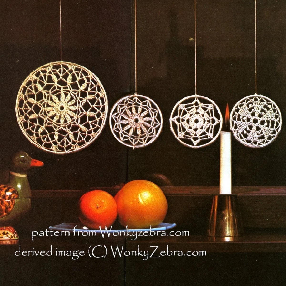 Four white hanging crochet circles with a snowflake in the center. Each circle has a different snowflake above a plate of oranges.