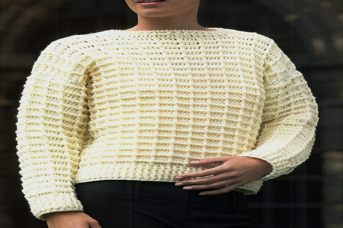  Woman wearing a chunky cream waffle stitch crochet jumper with long sleeves and black bottoms.
