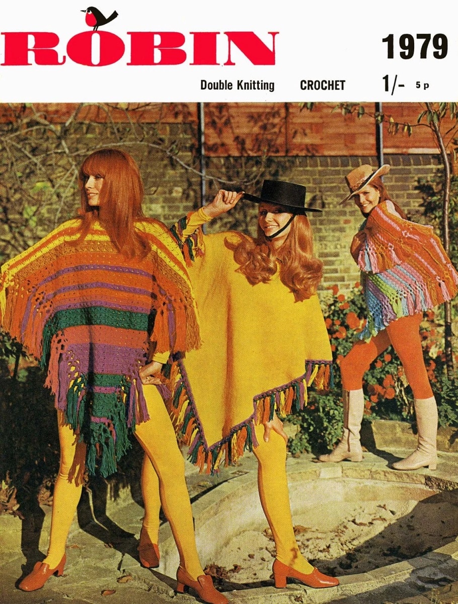Two redhead women wearing 60s style pinchos with yellow, red, orange, and green colors and tassels in the same colors.