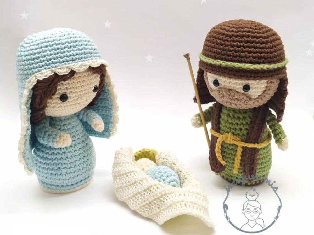 Short crochet Mary and Joseph dolls with oversized heads standing with a baby Jesus in a white basket in between them.  