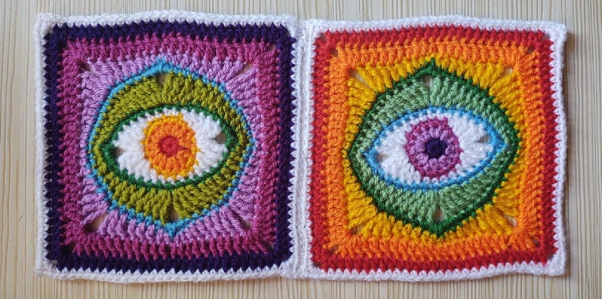 A purple, blue, and green crochet square with an eye in the center next to a yellow, orange, red, green, and blue square with the same design.