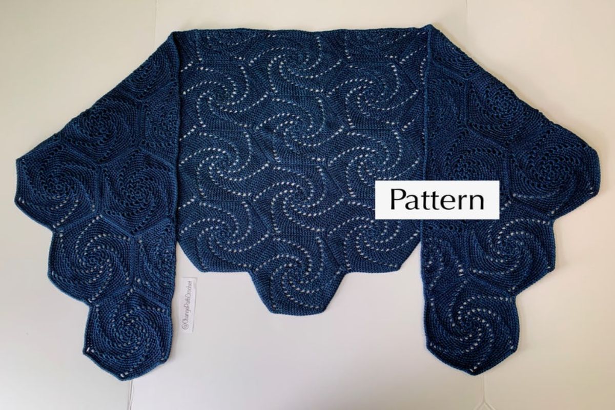 A cropped crochet navy blue shawl with a wave pattern and zig-zag edges all over on a white background.