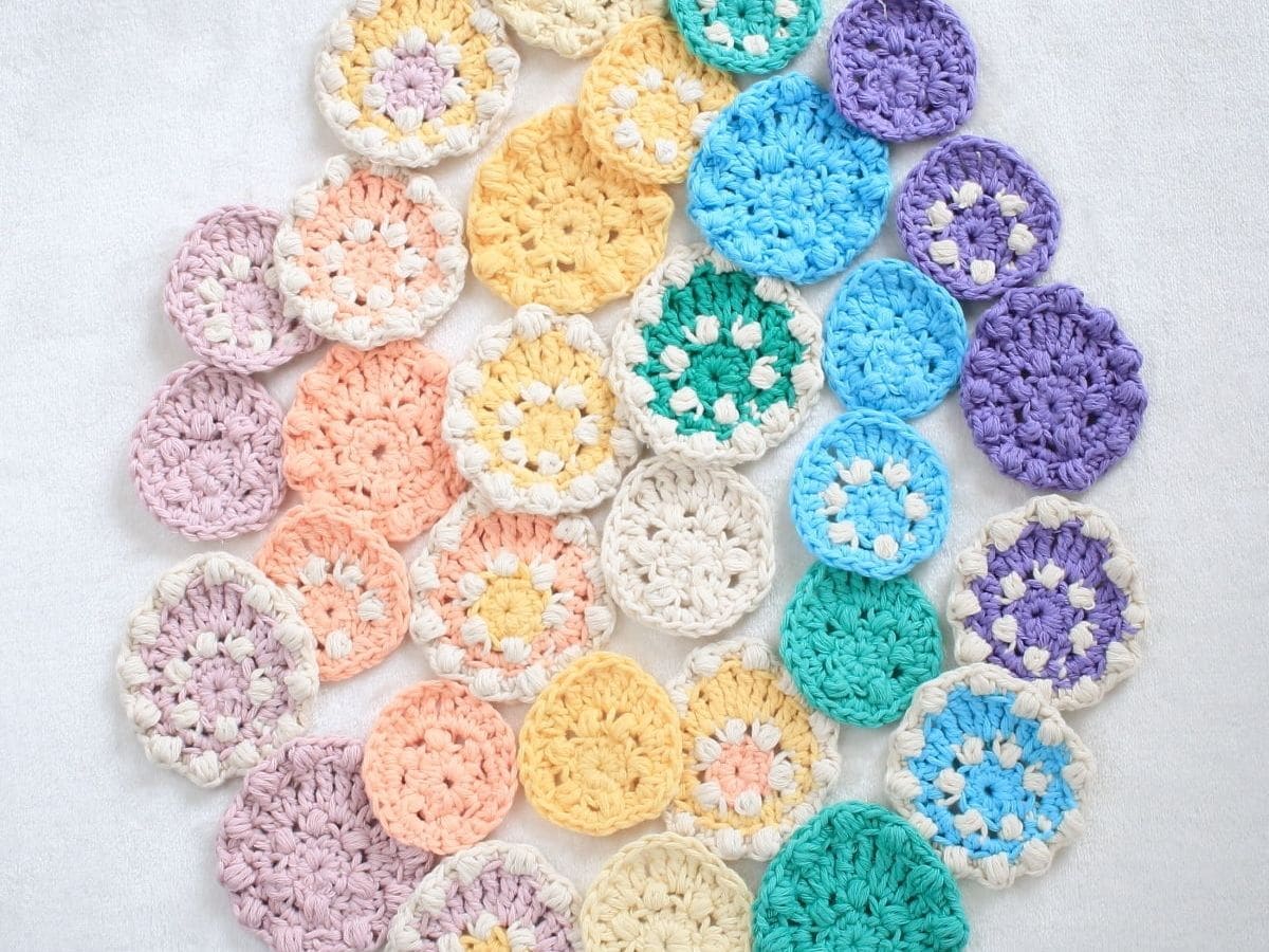 A range of pastel-colored egg-shaped crochet designs in a range of sizes are scattered on a white background. 