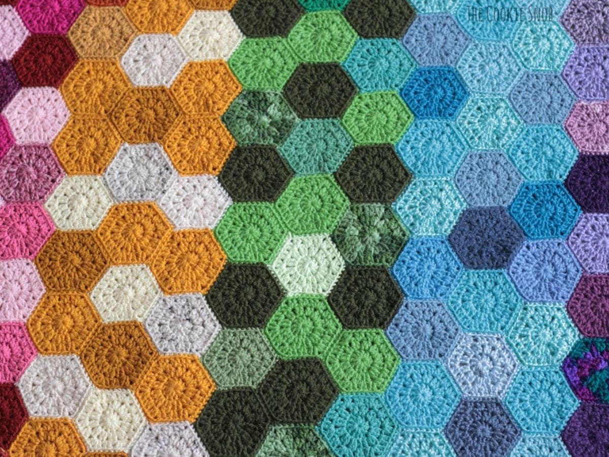 Hexagon crochet pattern featuring pink, purple, blue, green, orange, gray, and cream hexagons attached to each other. 