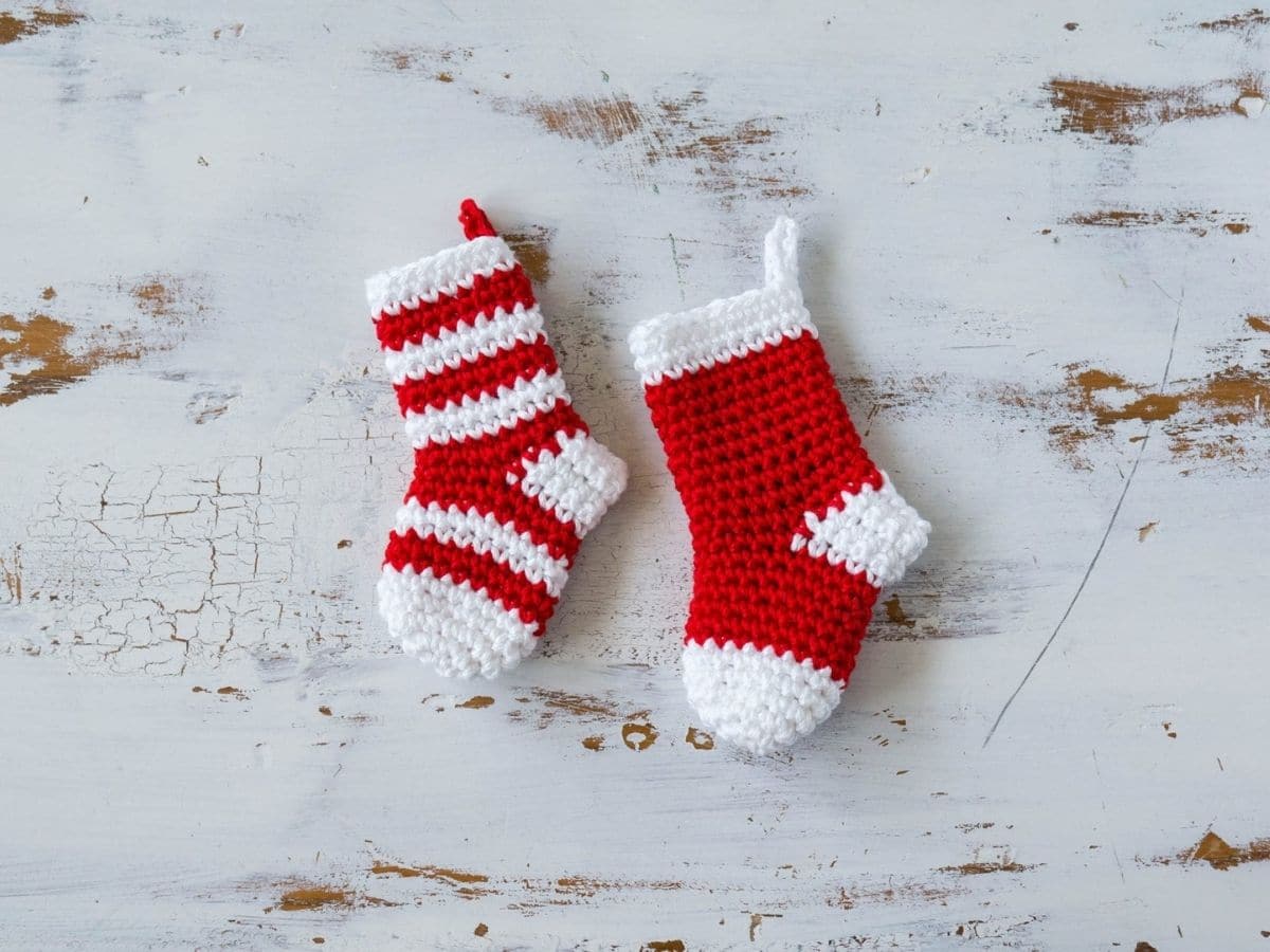 Red and white striped mini stocking and a red and white mini stocking on a white background. Both stockings have loops to hang them. 
