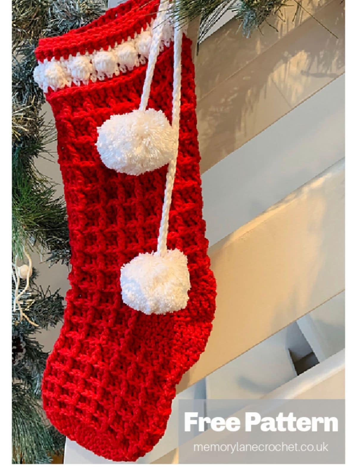 Large red waffle stick stocking with white detailing along the top and two white bobbles hanging on a white banister with decorative pine.